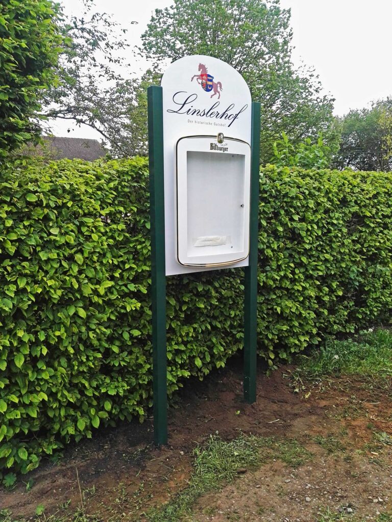 Schaukasten-Anlage für den Linslerhof miz zweibeinigem Ständerwerk, Logoanbringung und Schaukasten
