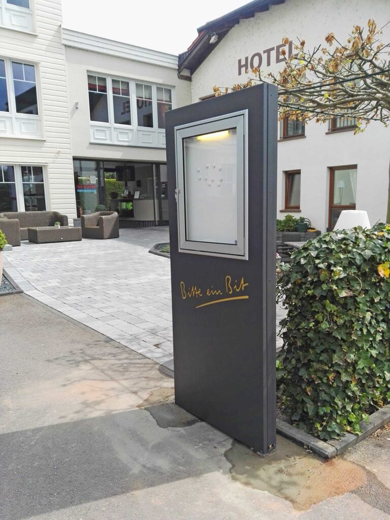 Pylone mit Schriftzug "Bitte ein Bit" und Schaukasten für Restaurant-Aushang