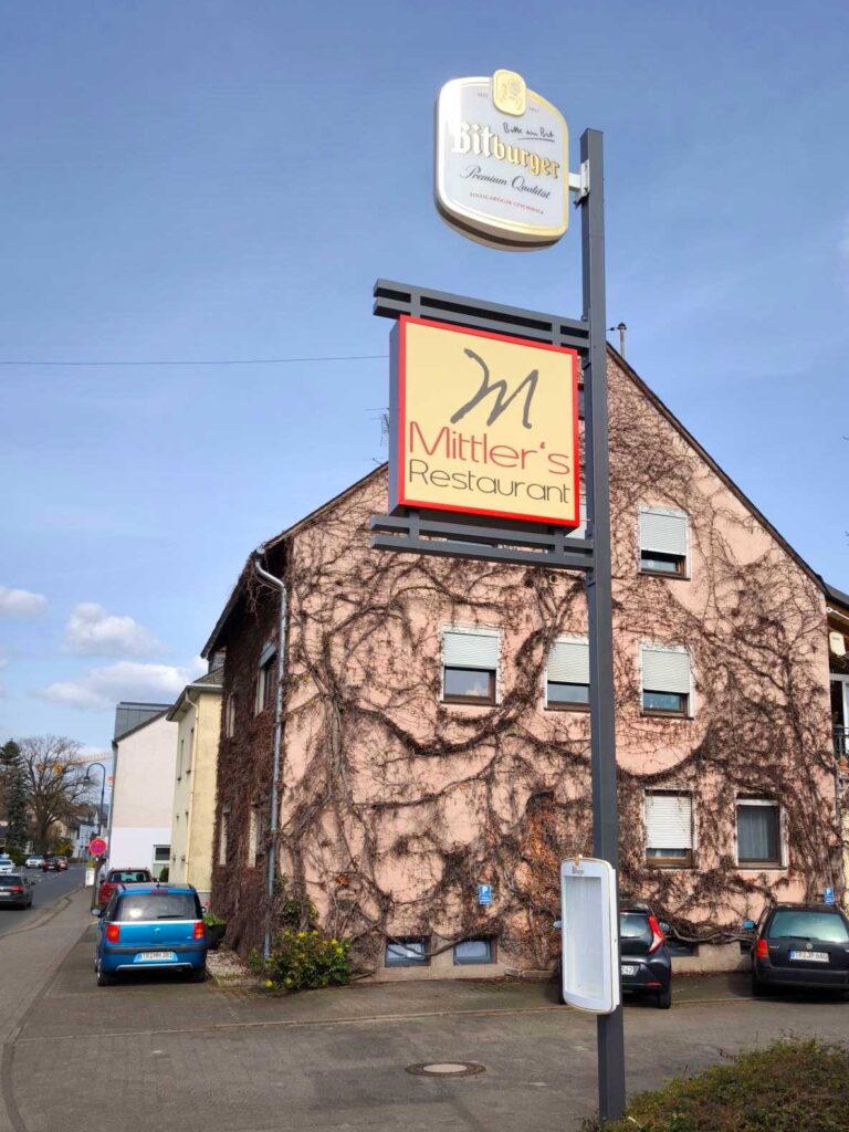 Schildanlage mit Bitburger-Werbung und einem Schaukasten für Mittler's Restaurant