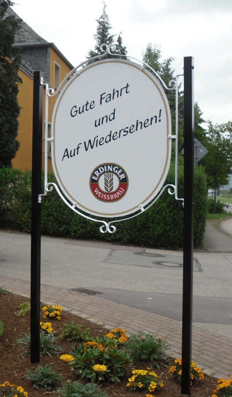 Schild mit Ornamentabschluss mit "Gute Fahrt und Auf Wiedersehen" mit Logo Erdinger Weissbräu