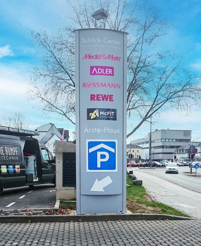 beleuchtete Pylonenanlage für das Schlick-Center mit mehreren Logos und Hinweis auf ein Parkhaus