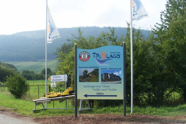 Schildanlage mit abgebogtem Abschluß und Fahnen für Triolago